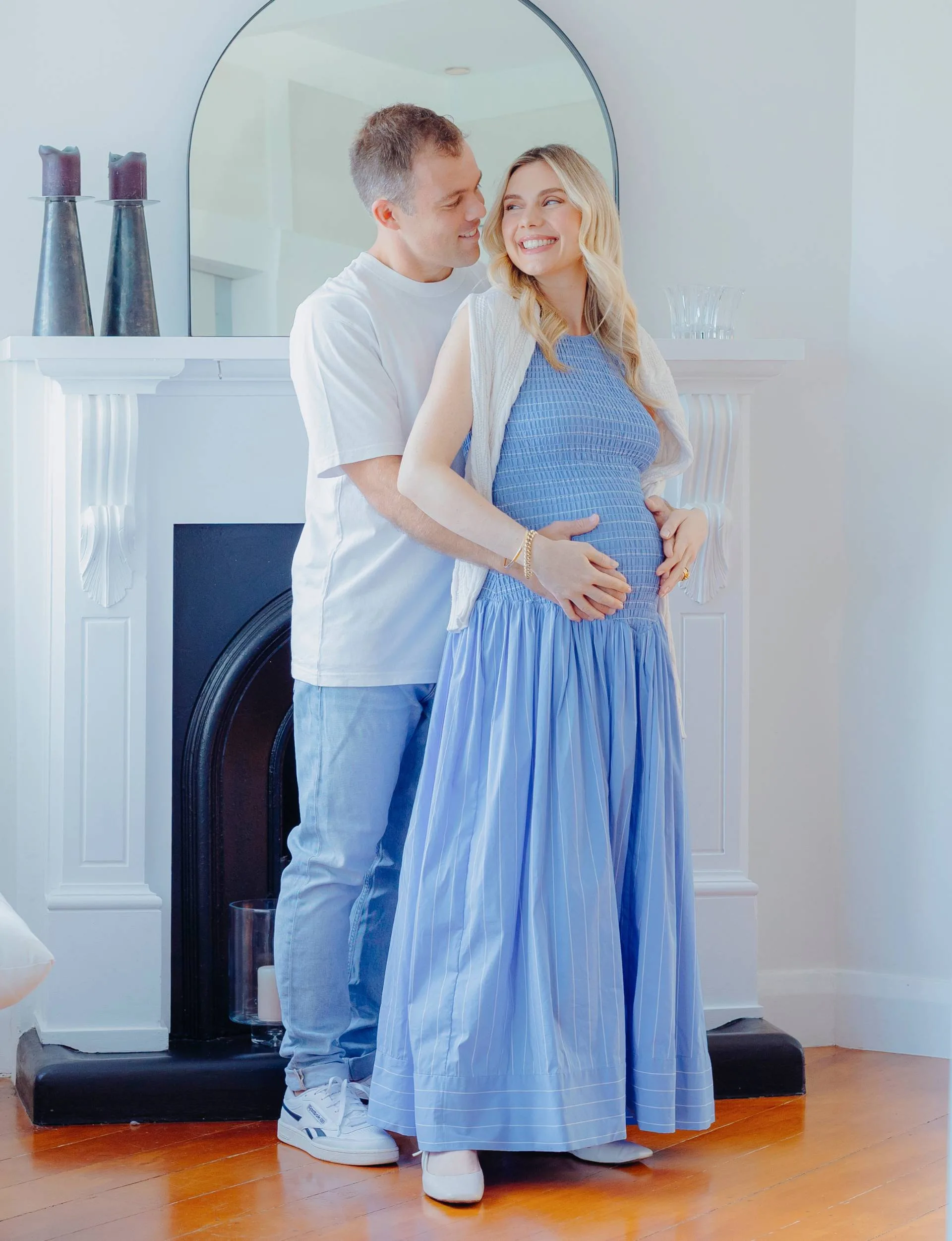 Caitlin Crisp cradling her baby bump with husband Andrew
