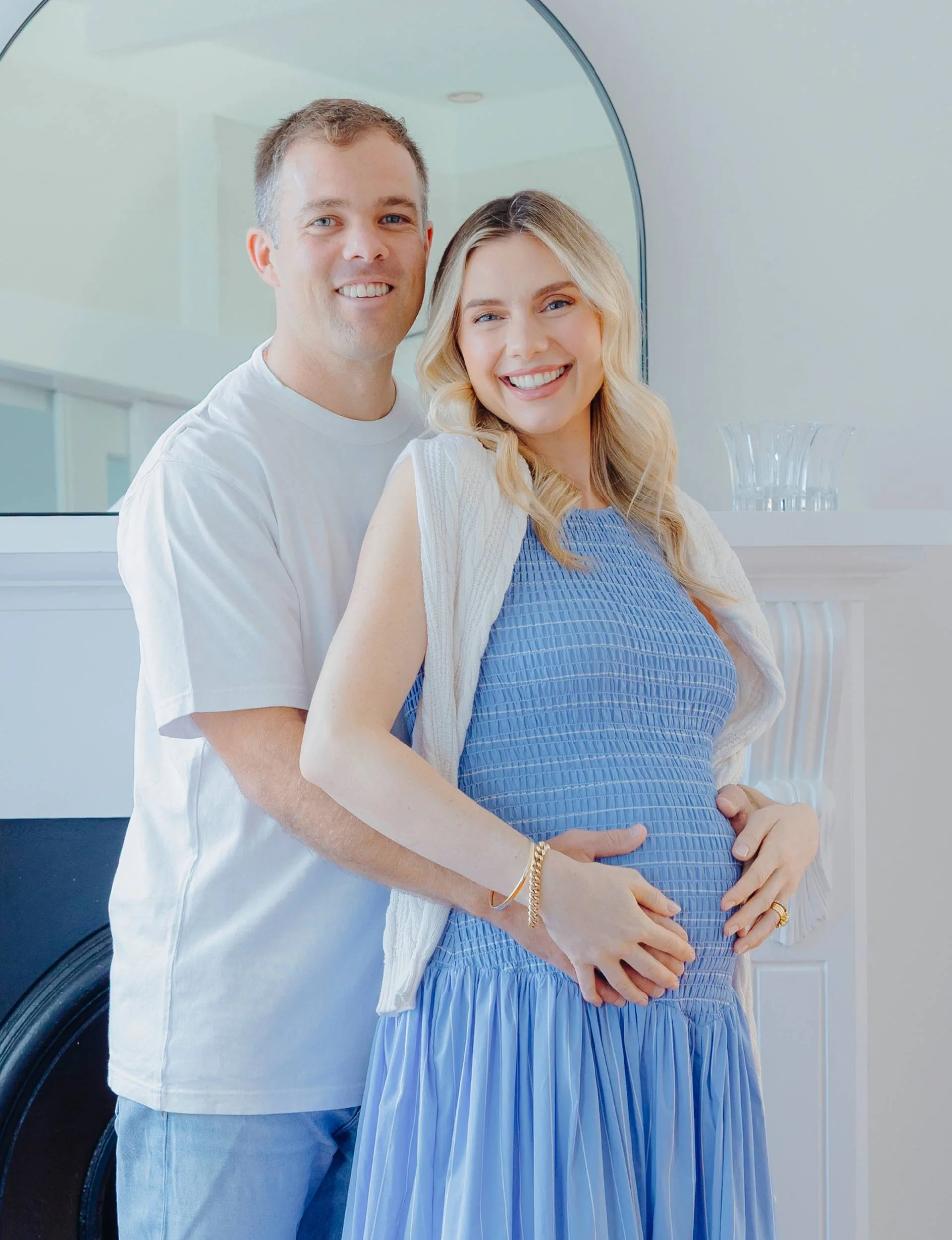 Caitlin Crisp cradling her baby bump with husband Andrew