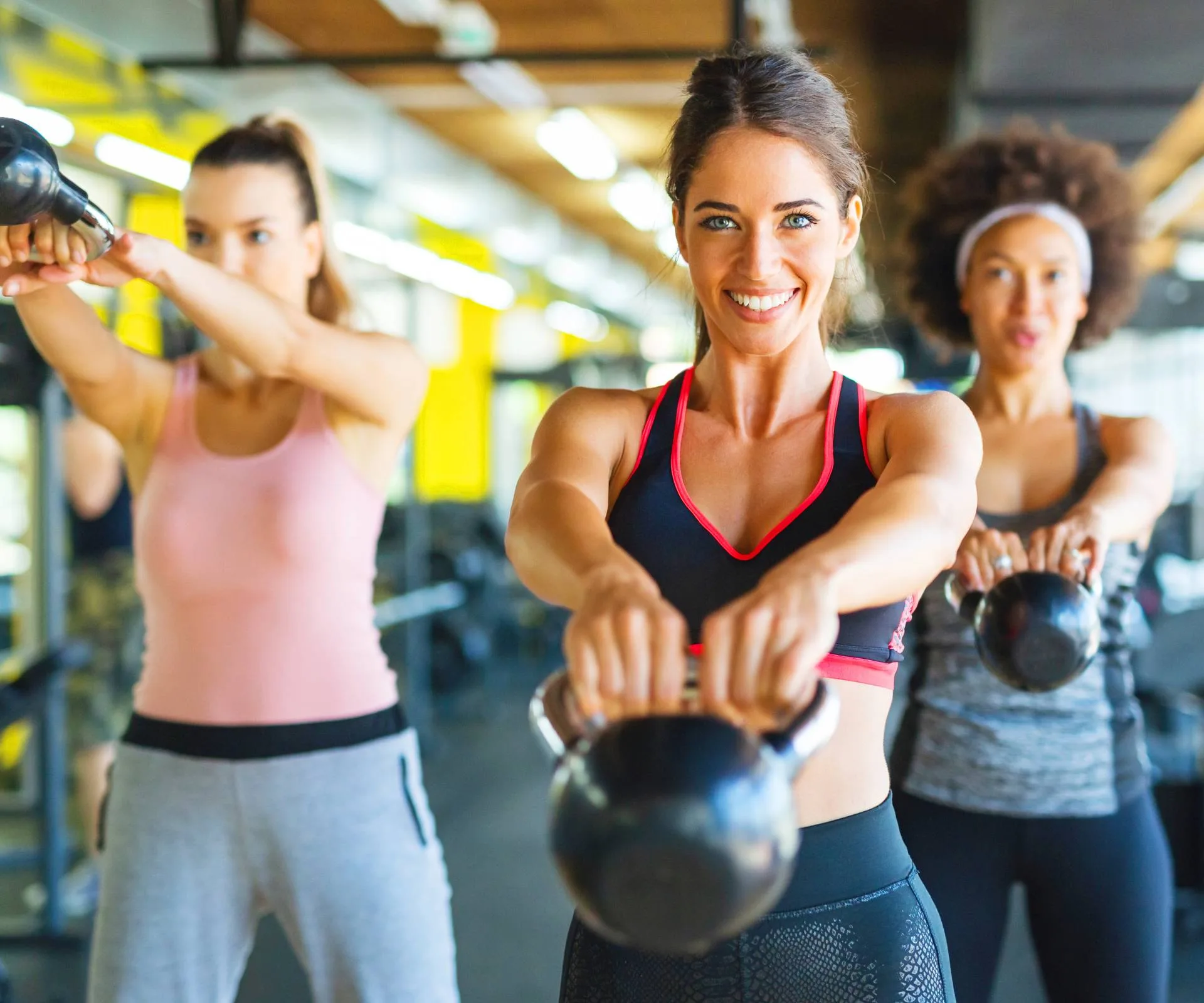 Three women swinging kettle bells during their exercise and fitness session