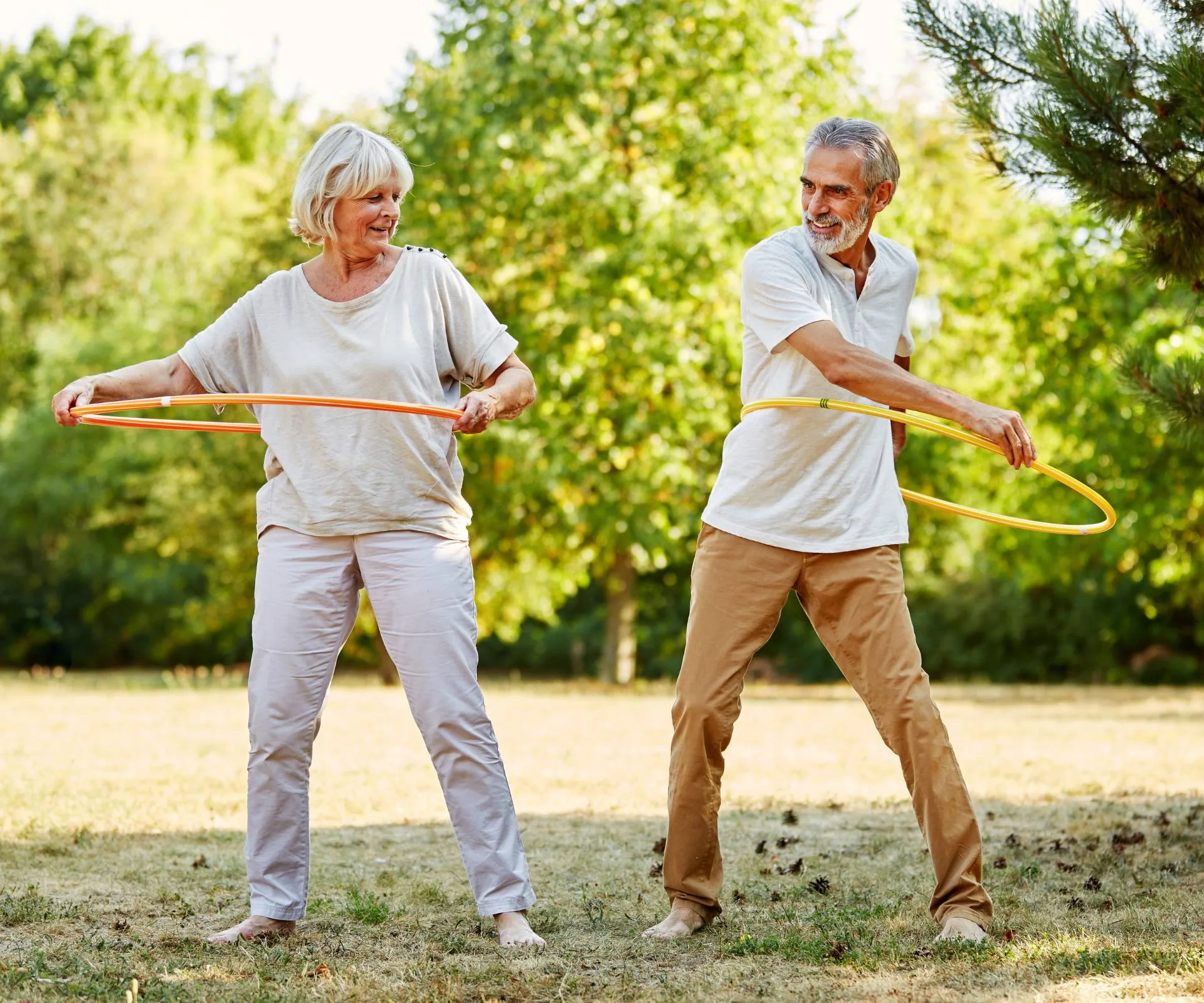 An elderly couple hula hooping