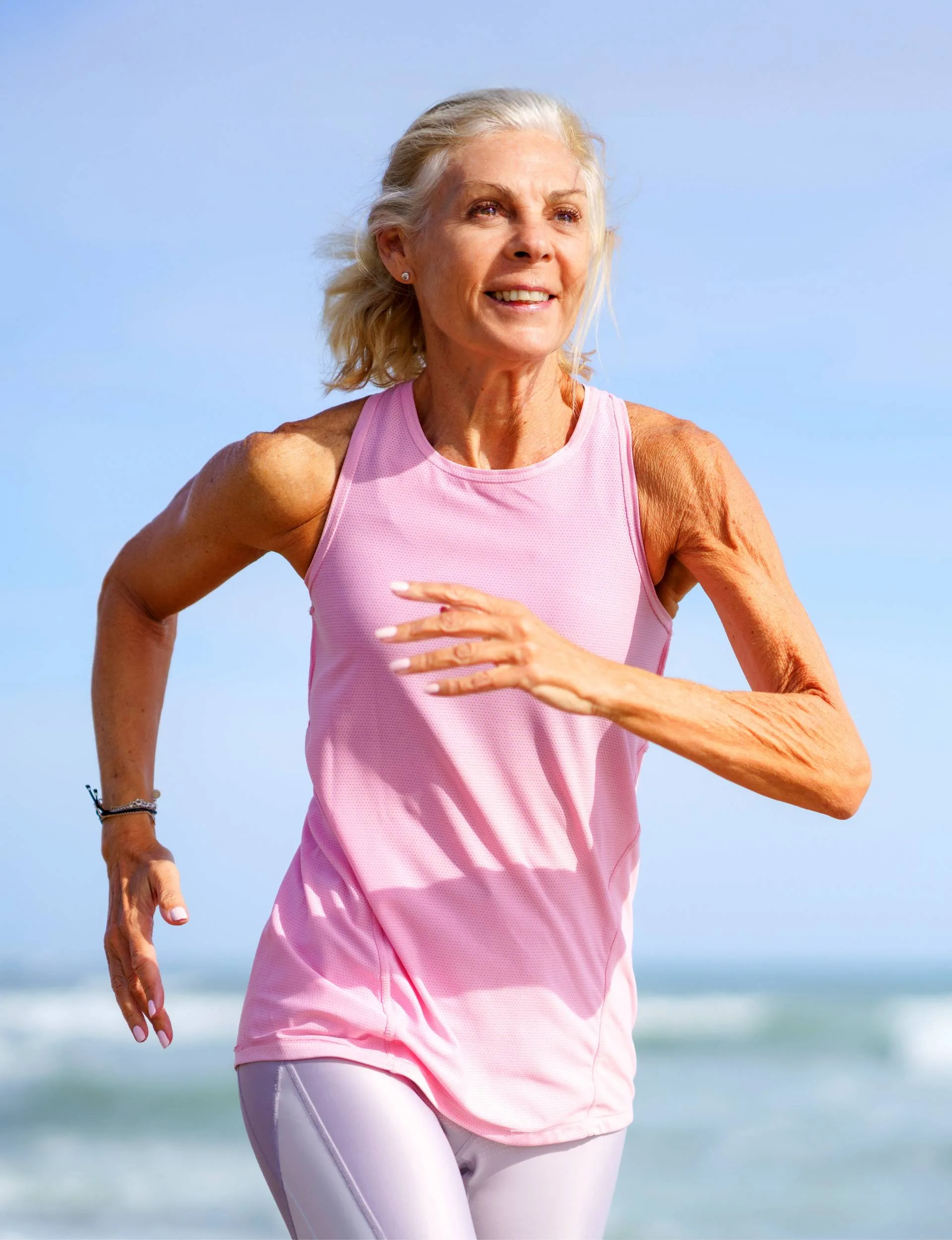 An elderly woman running up a beach