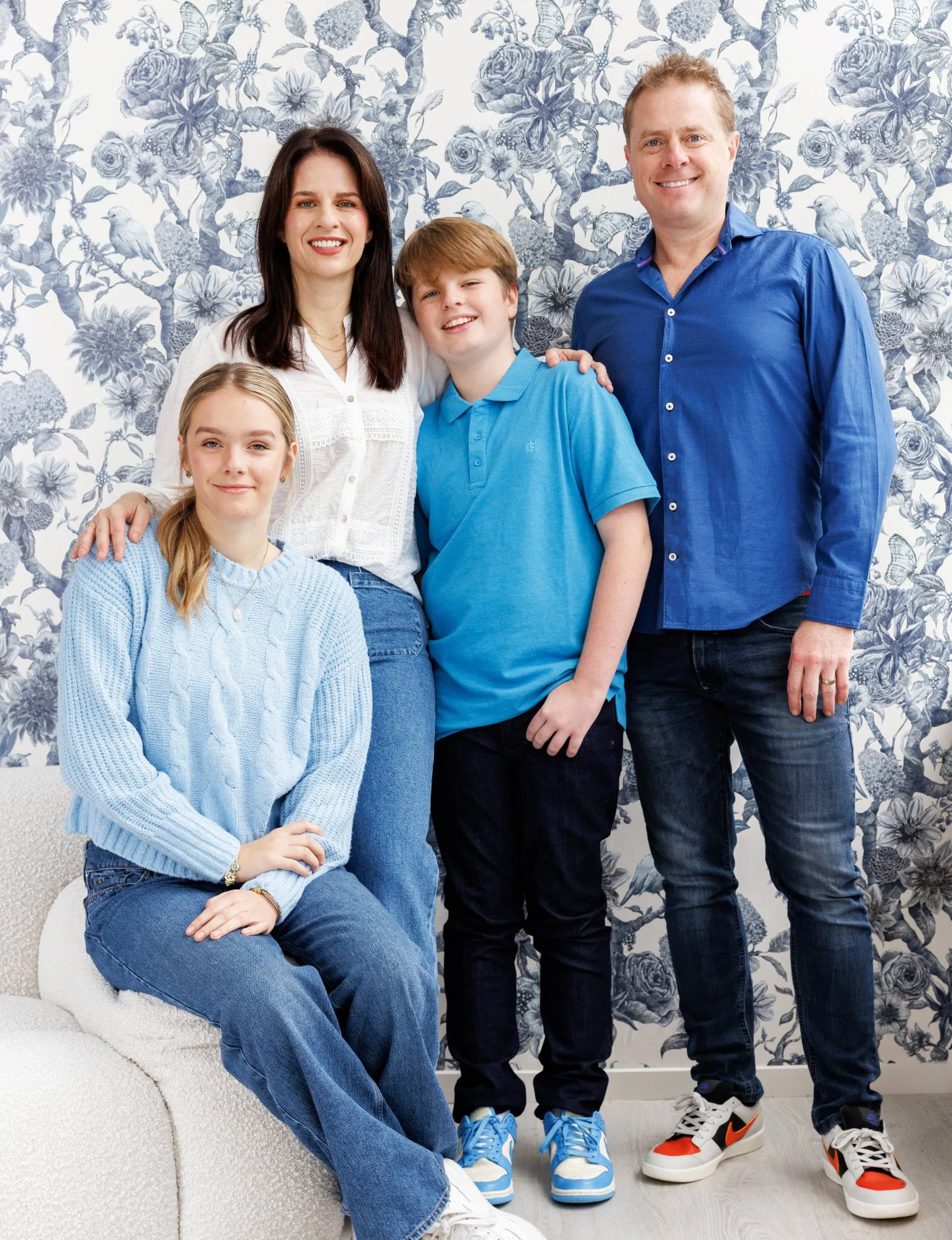 Erica Poppelbaum with her family in front of a blue and white wallpapered wall