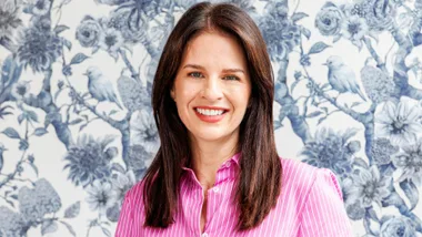 Erica Stanford in front of a blue and white wallpapered wall
