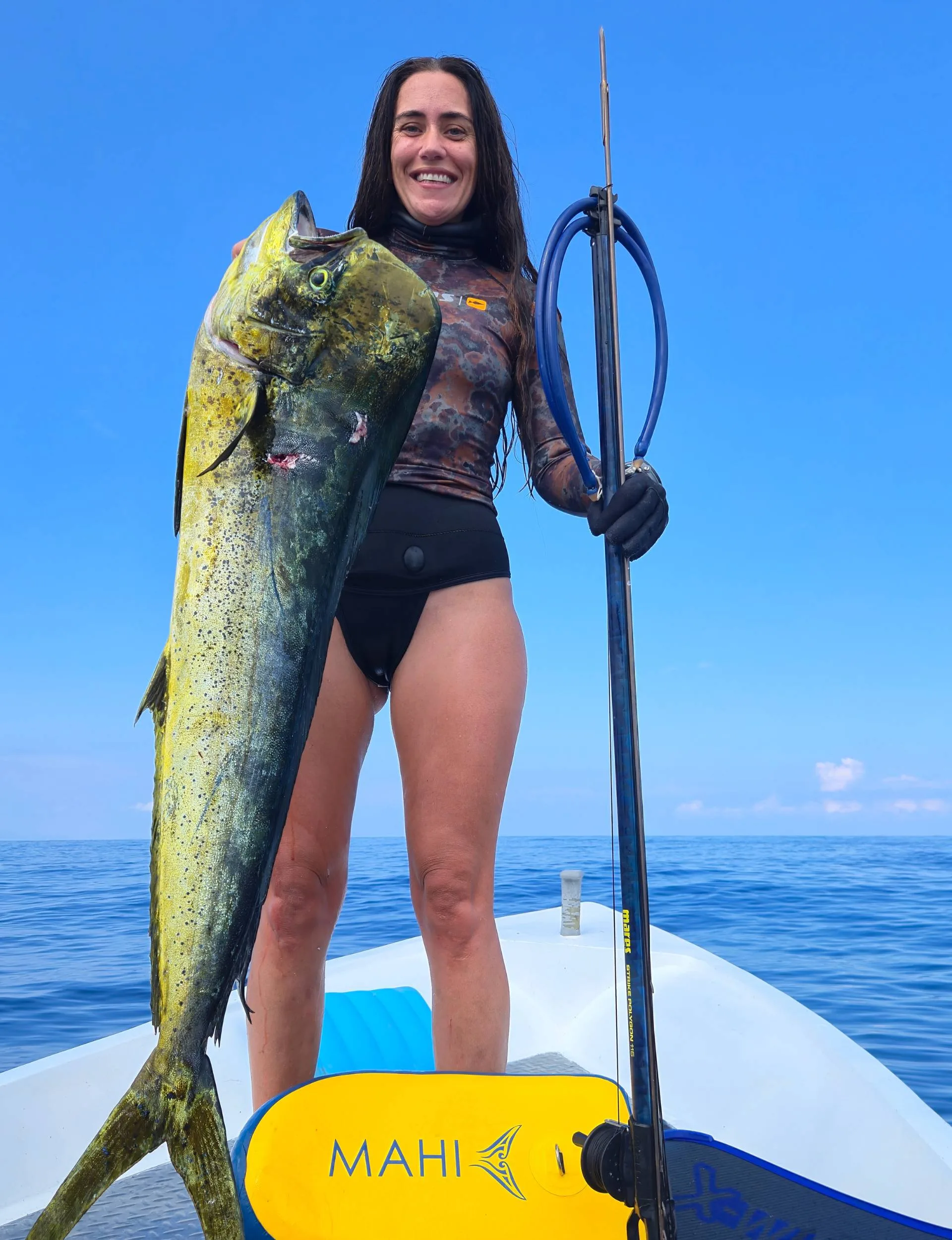 Benedicta holding up a large fish on a small boat