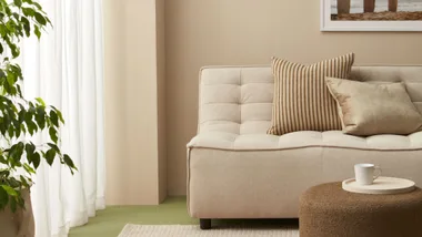 The use of a muted biophilic green on the floor livens up the restrained palette in this neutral living room