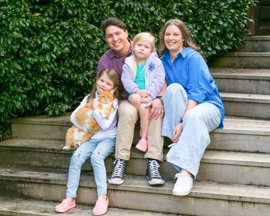 Family sitting on stairs with ginger cat