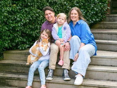 Family sitting on stairs with ginger cat