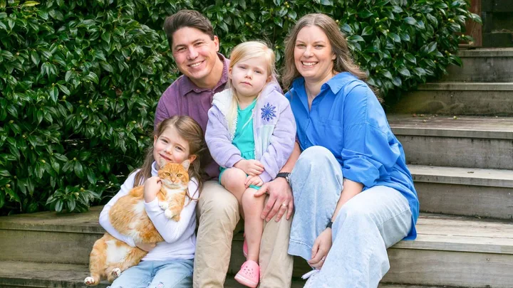 Family sitting on stairs with ginger cat
