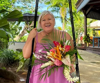 jay-jay feeney in pink dress sitting on swing with flowers in her hands