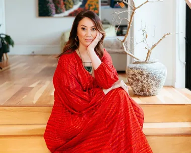 miriama kamo sitting on stairs wearing red dress