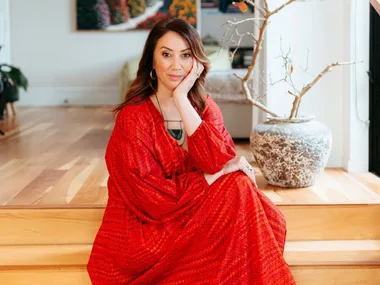 miriama kamo sitting on stairs wearing red dress