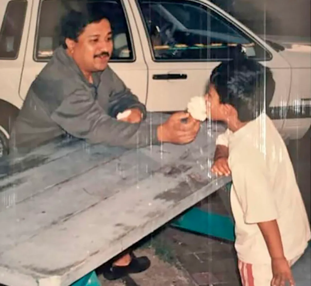 Darrsh as a boy with his dad sitting at a park bench