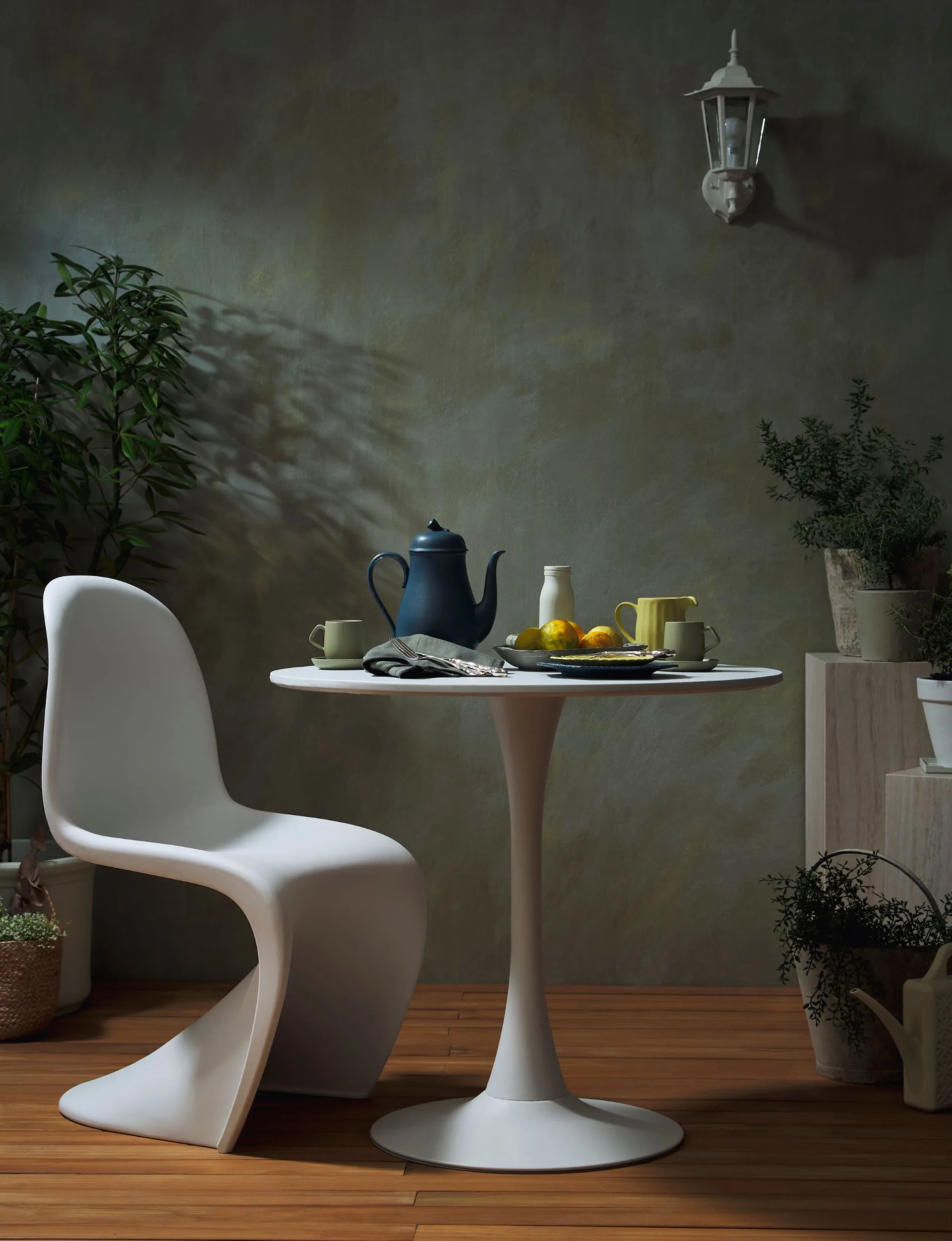 Moody colours brings an edgy cosiness to outdoor spaces. Wall painted in different shades of grey and green, with white furniture
