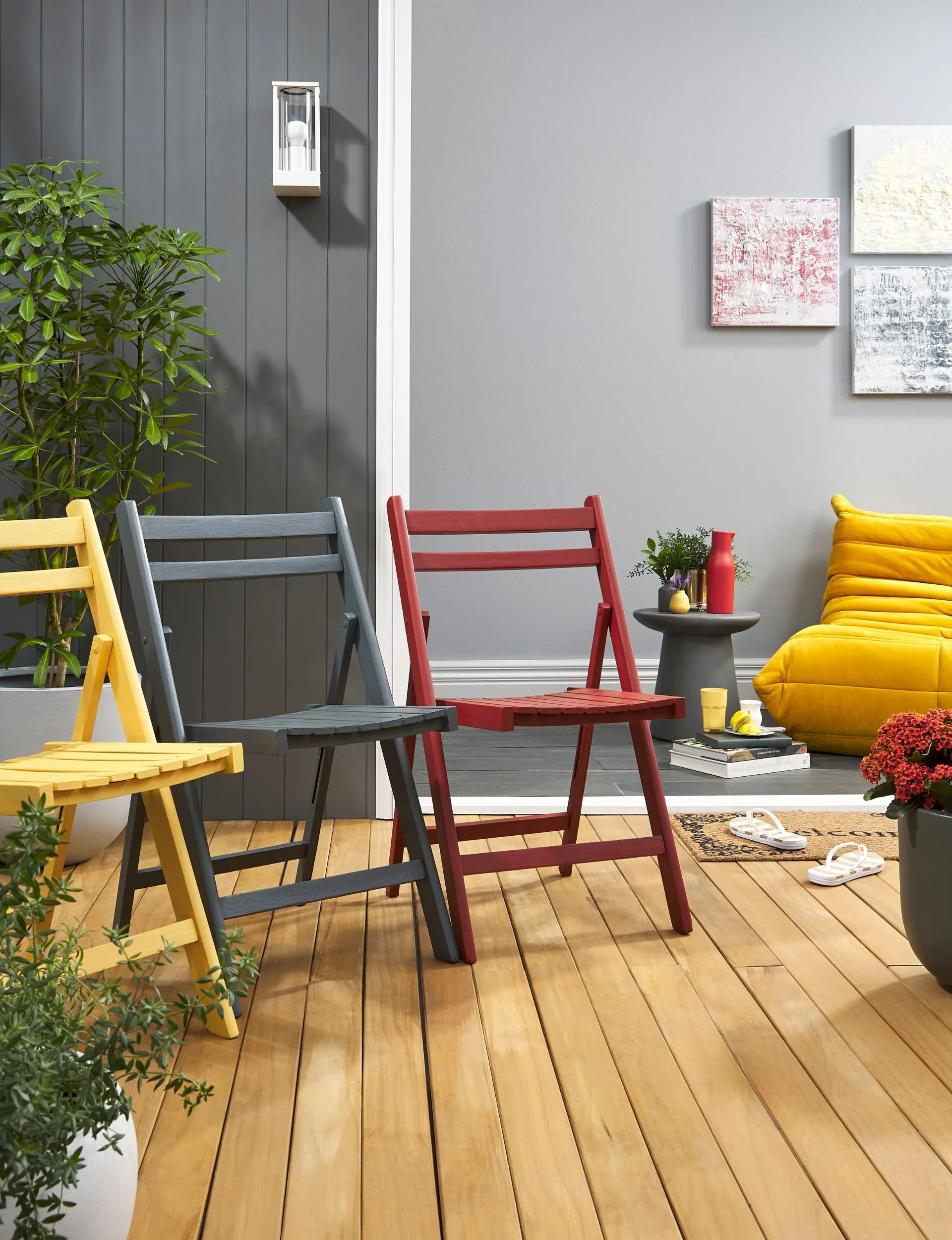 Using bold sunny colours in furniture adds warmth to outdoor spaces. Outdoor chairs painted in yellow, grey and red, stand out against the woodstained deck