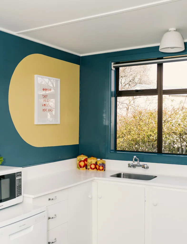 The kitchen in the 2025 Resene Colour Home Awards winning home is painted in a teal colour with a fun golden arch