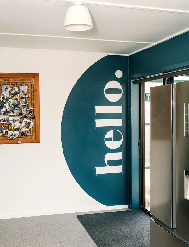 A cheerful welcome greets visitors to the 2025 Resene Colour Home Awards winning home with an half circle painted in blue with 'Hello' painted in white