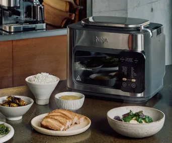 ninkja combi multicooker on bench with plates and bowls of food