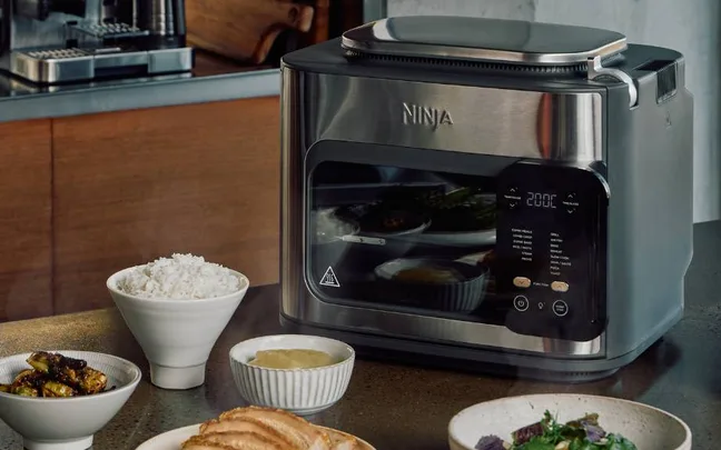 ninkja combi multicooker on bench with plates and bowls of food
