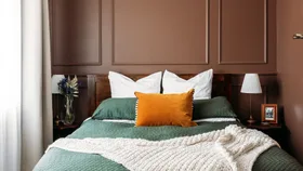 Rich brown paint used on walls in this bedroom in Wellington villa, green bedspread with orange accent cushion