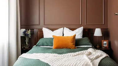 Rich brown paint used on walls in this bedroom in Wellington villa, green bedspread with orange accent cushion