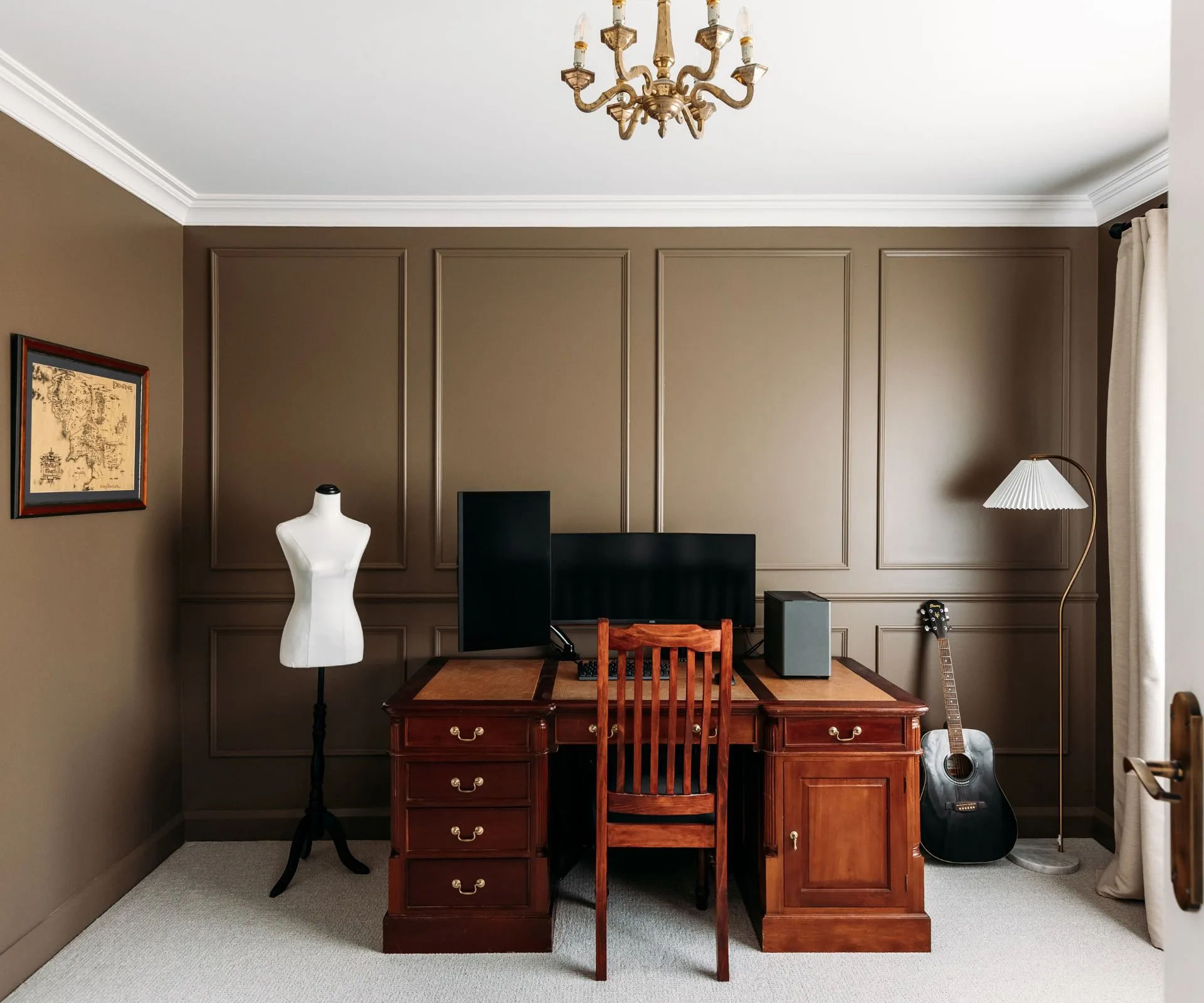 The office room is painted a light brown beige, with a wooden desk in the middle