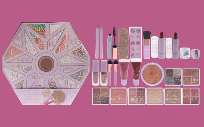 A hexagonal makeup advent calendar on a pink background features numbered sections with various cosmetics, including lipsticks, brushes, and nail polishes.
