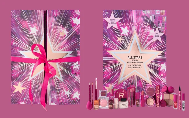 Pink and purple Revolution Beauty advent calendar with a starburst design, tied with a pink ribbon. It includes makeup products like lipsticks and eyeshadows, conveying a sense of excitement.