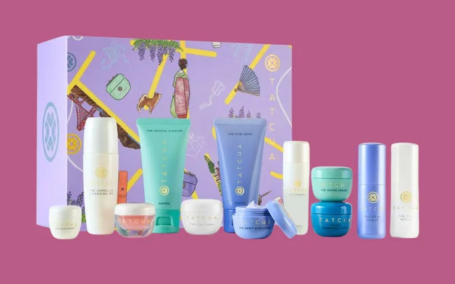 A collection of Tatcha skincare products displayed in front of a decorative box with a purple design featuring Japanese motifs.