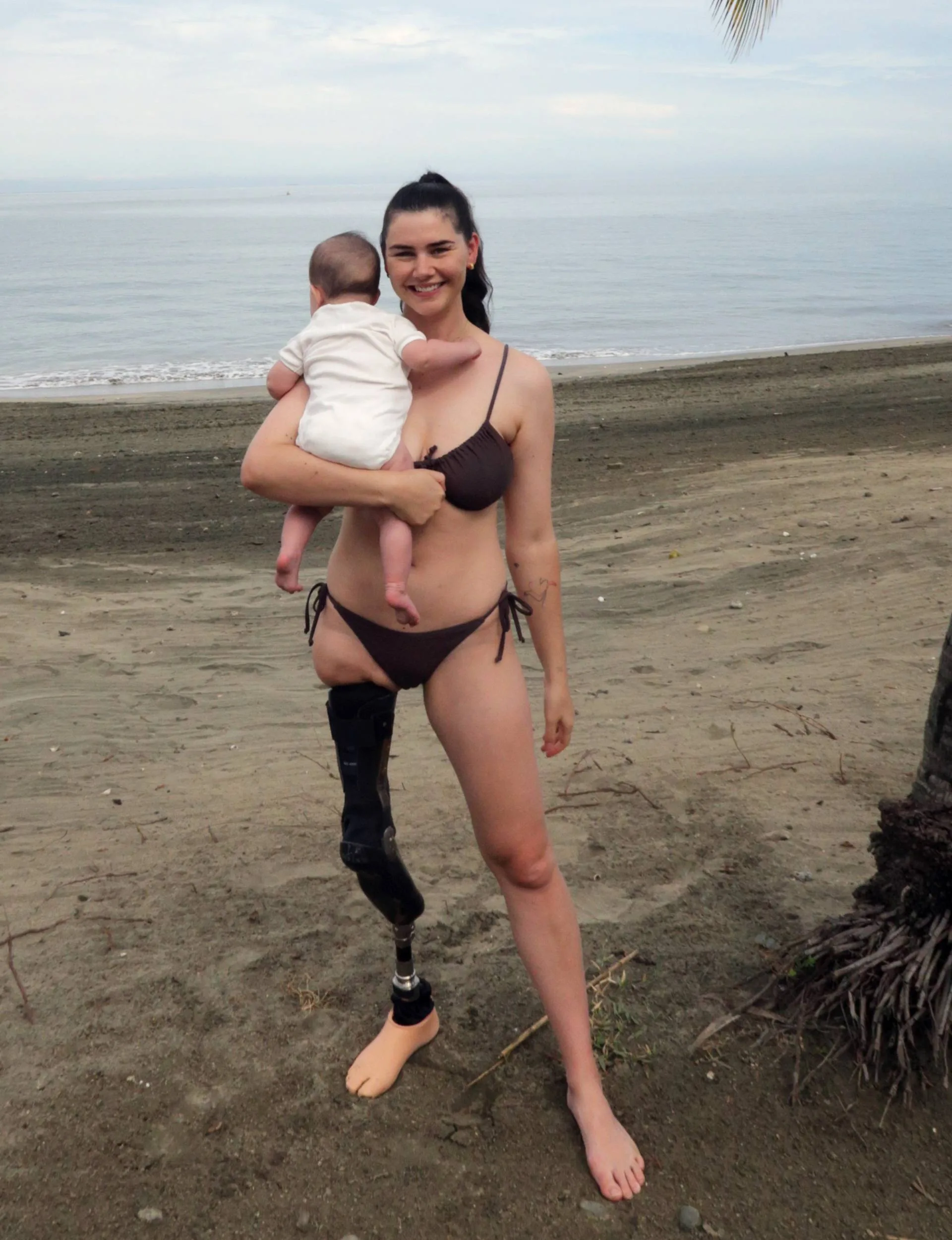 Woman on beach with baby in hand 