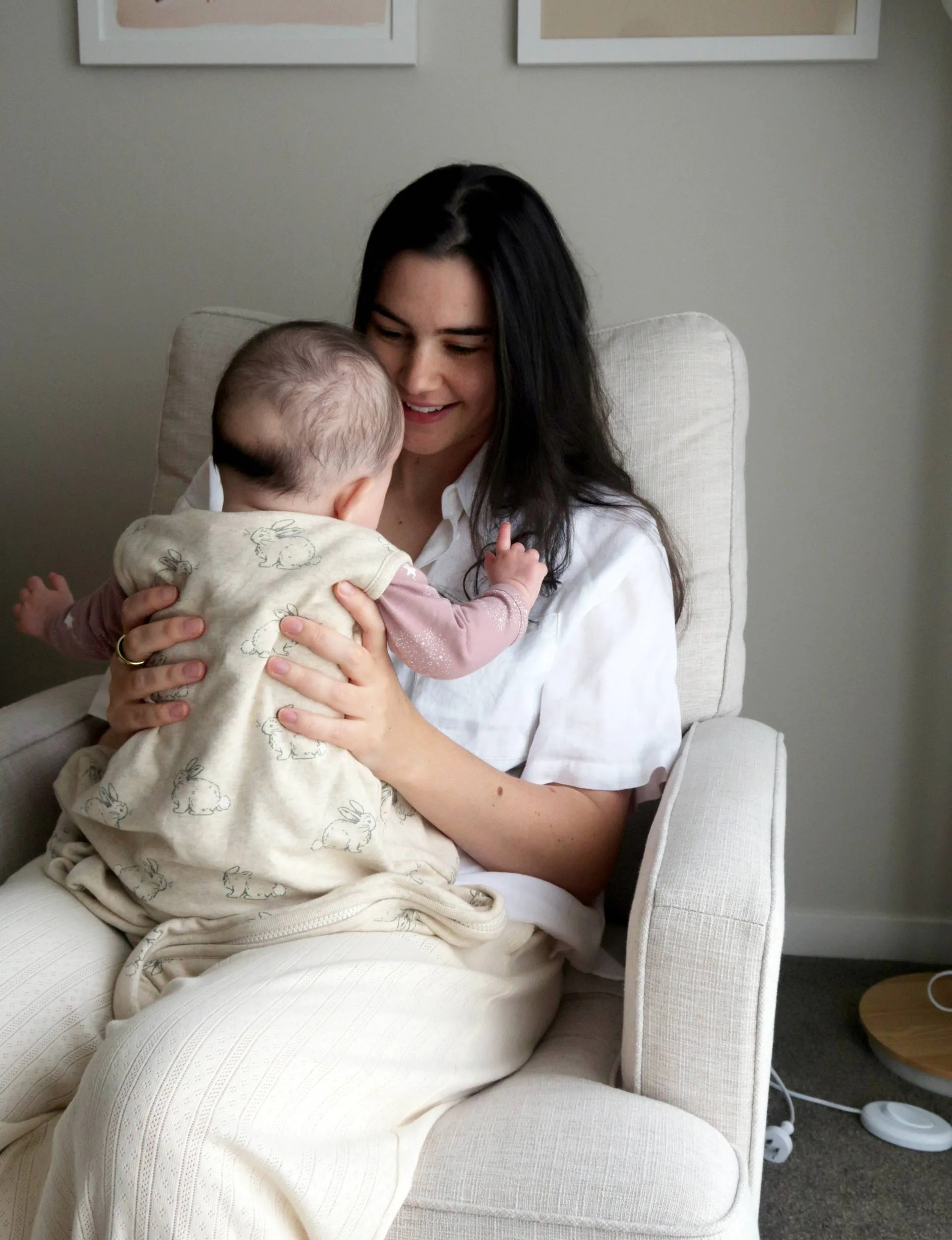 Mother sitting on cream chair holding baby 