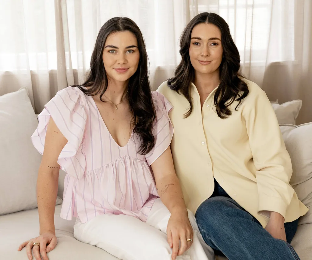 Two woman sitting on couch, one in pink and other in yellow