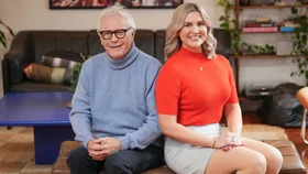 Man in blue jersey and woman in red shirt sitting next to each other