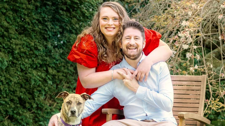 Woman in red dress and man in blue shirt with dog