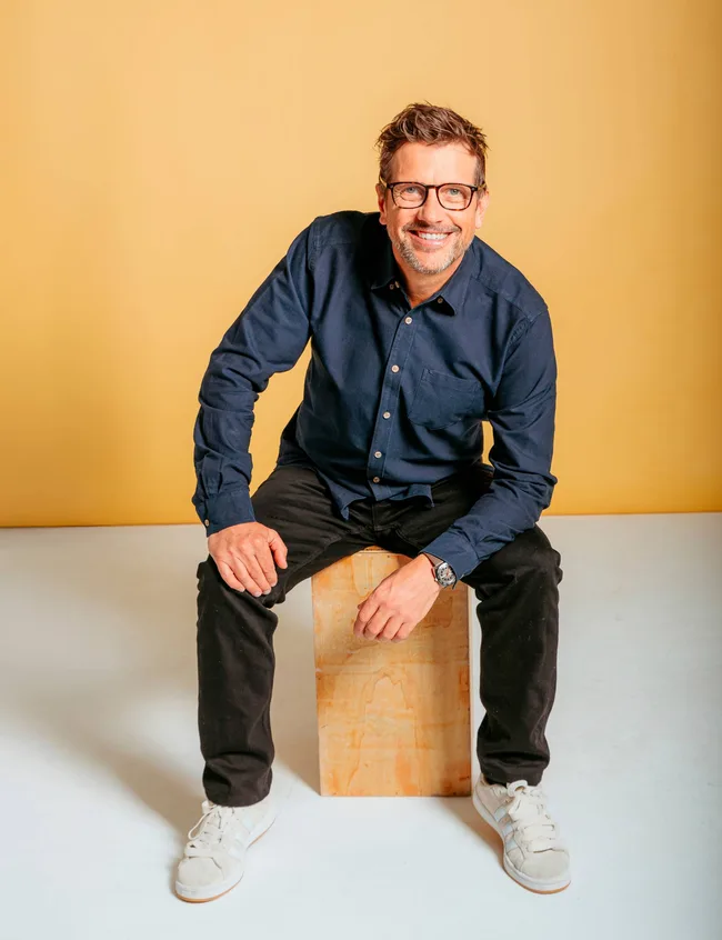 Man sat on box in blue longsleeve