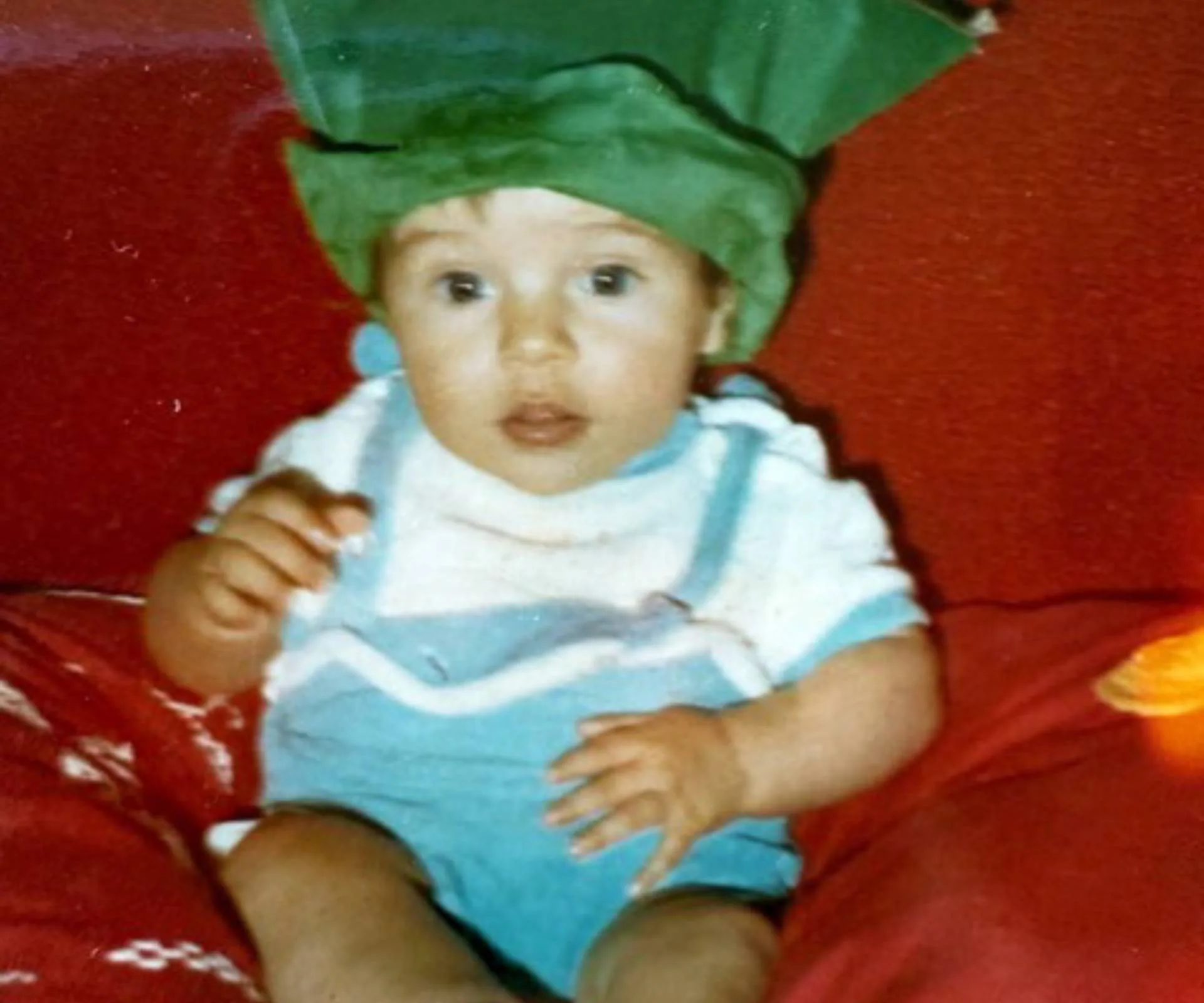 Baby in Green hat and blue overalls