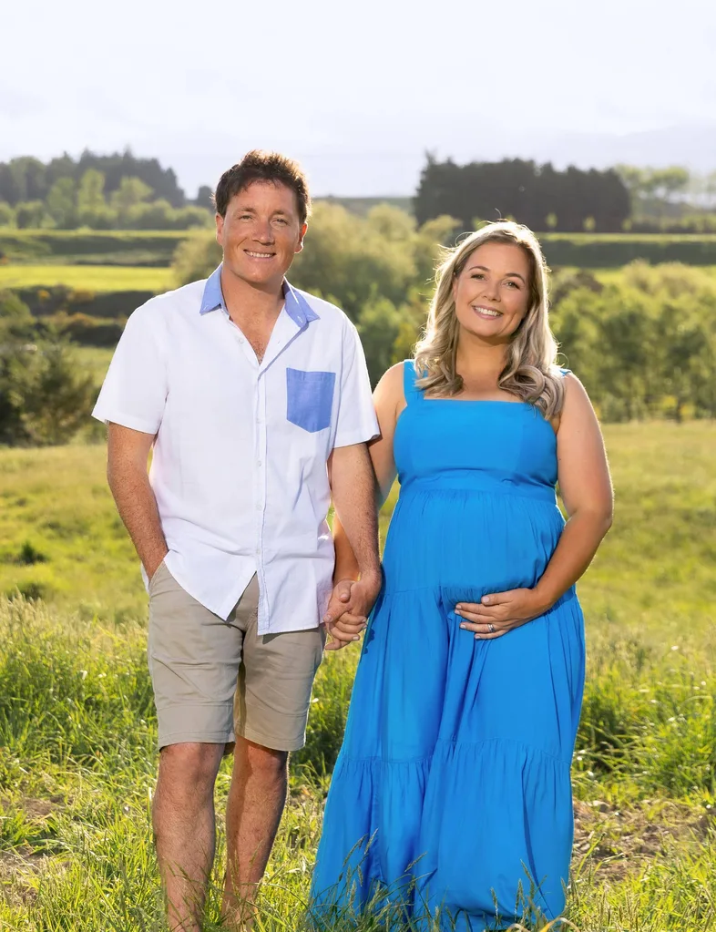 Alexa and Jason holding hands in the field showing baby bump
