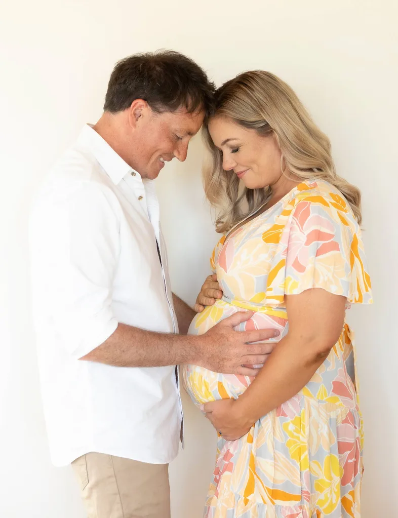 Alexa Cook and partner holding baby bump together and looking at it