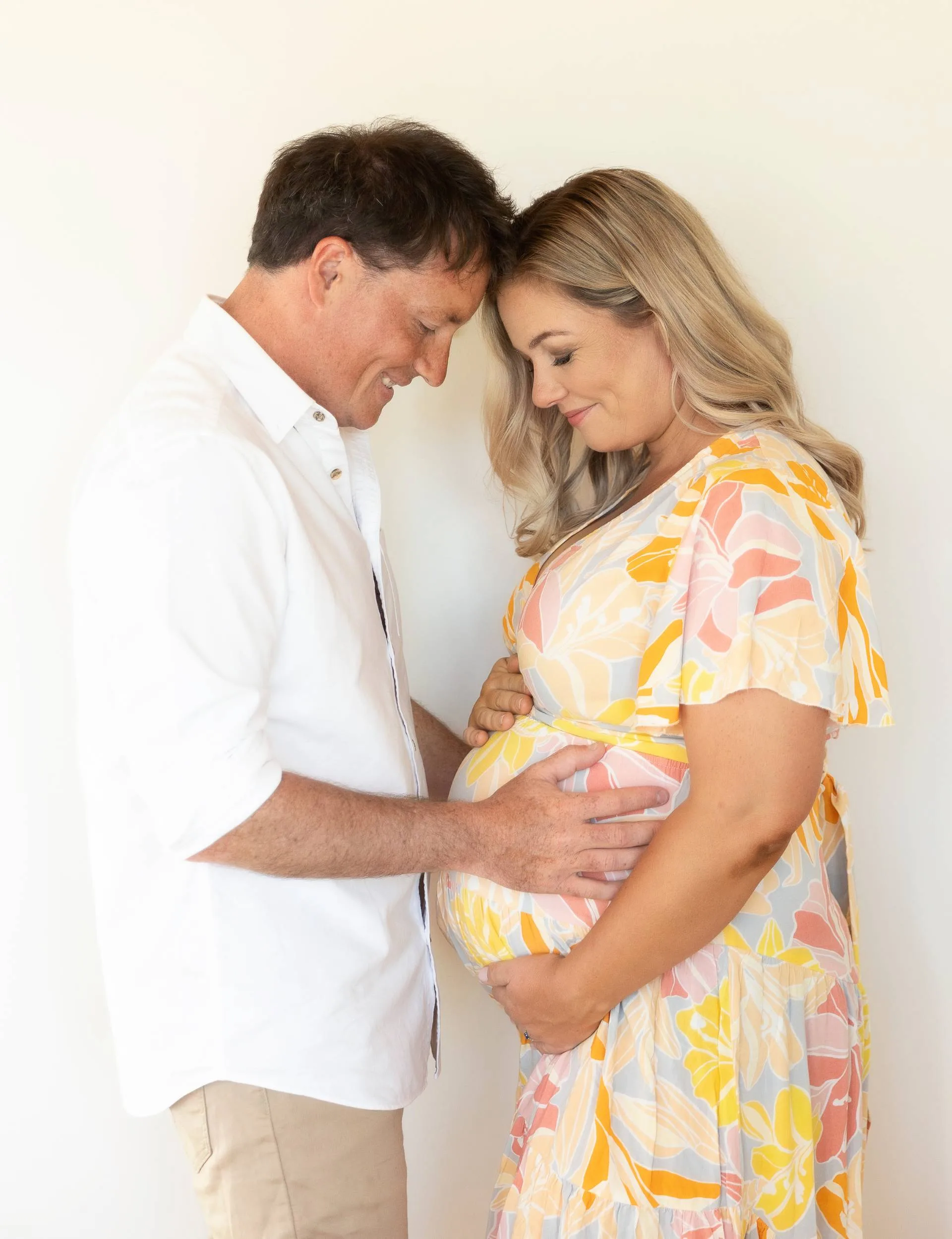 Alexa Cook and partner holding baby bump together and looking at it