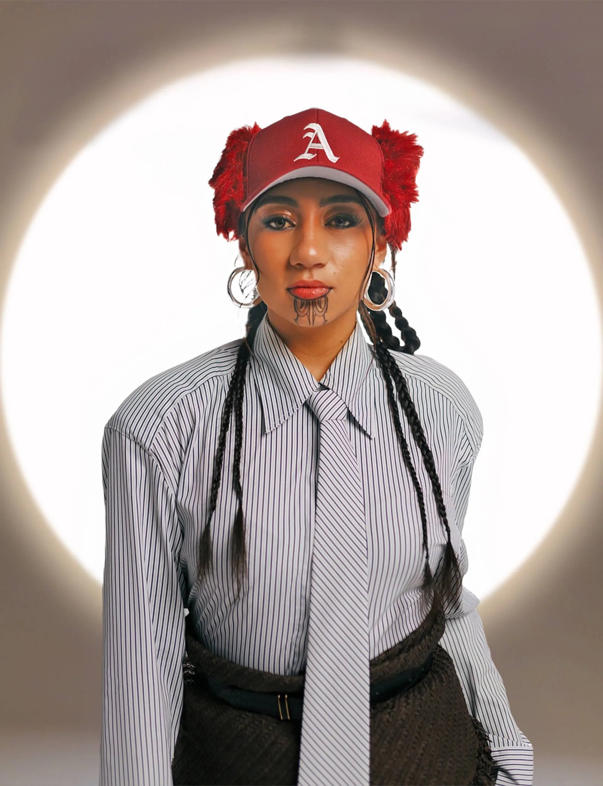 Ahikāroa in red hat with letter A and pinstripe shirt and tie
