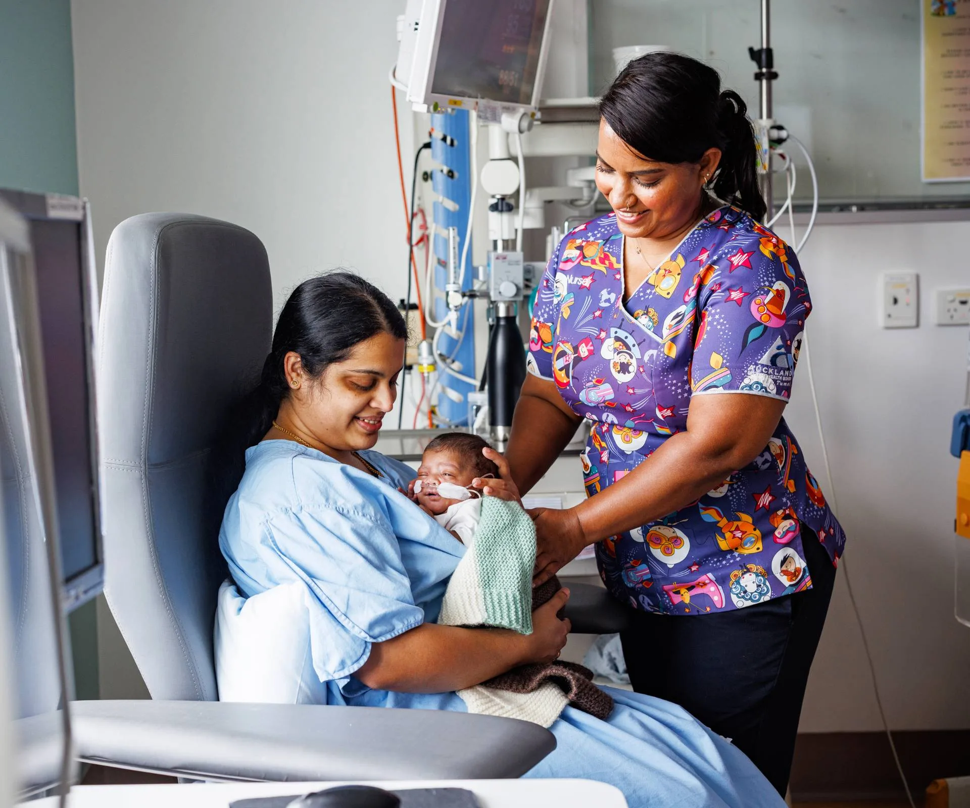 Arishma with patient holding baby in hospital room