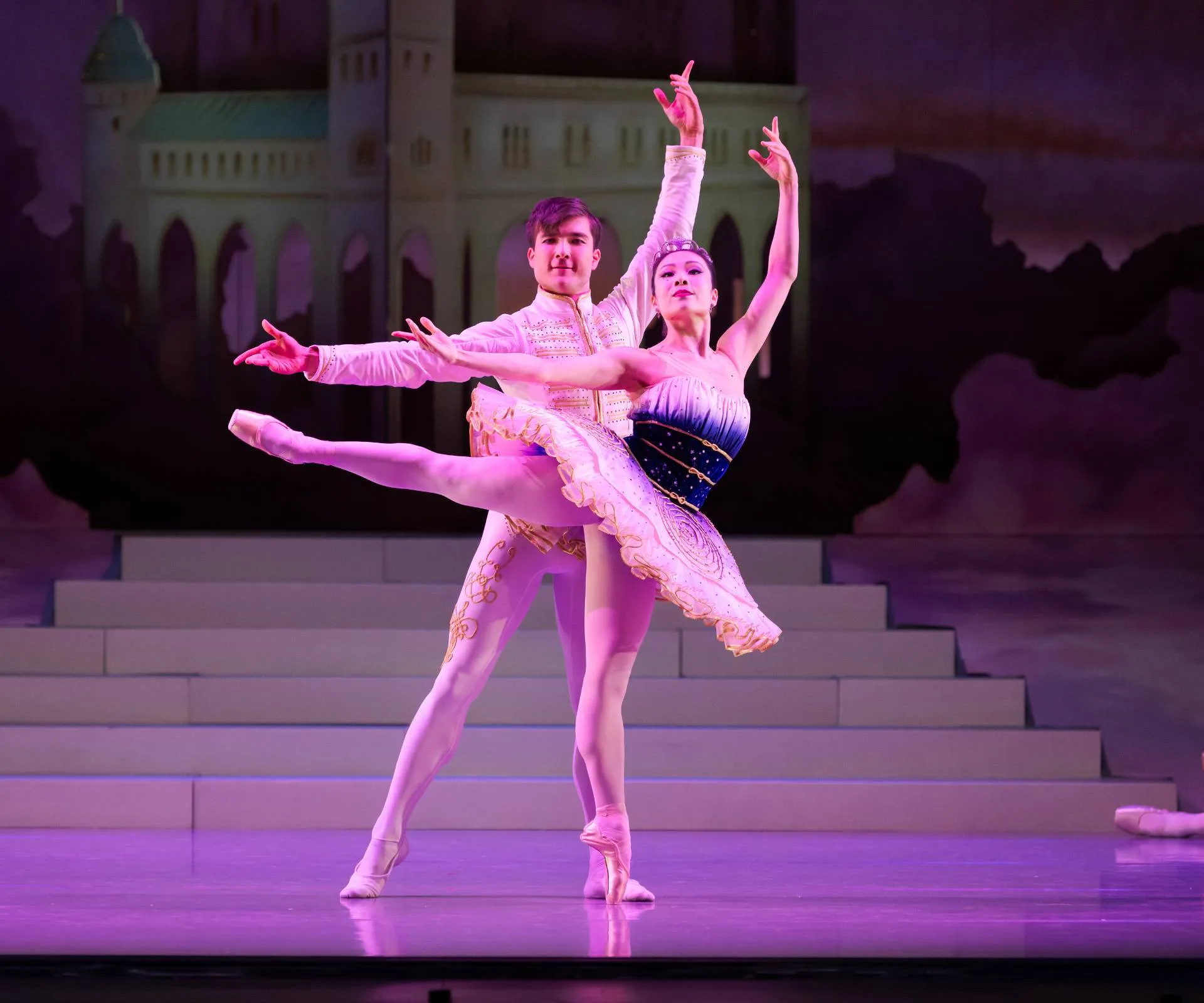 Ballerina in white and blue outfit and man in white and gold outfit posing