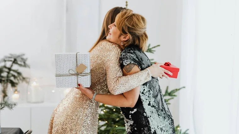 two women giving presents at Christmas and hugging