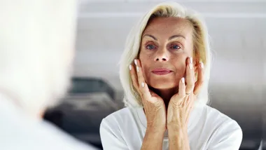 Middle aged woman applying skincare in the bathroom