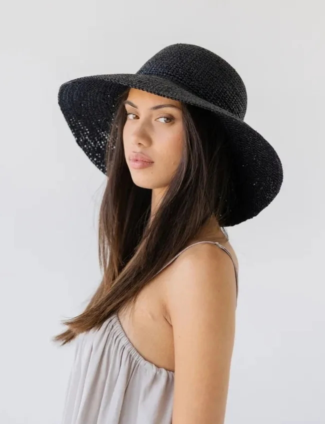 Woman wearing a wide-brim black raffia hat