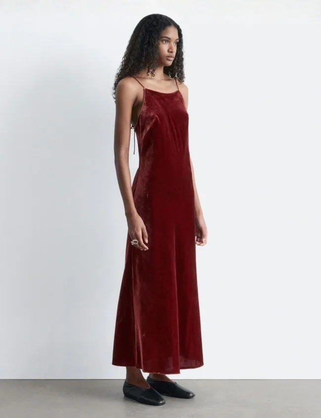 Woman wearing a midi length dark red velvet slip dress