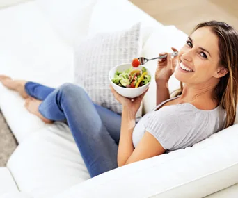 White woman smiling whilst eating salad