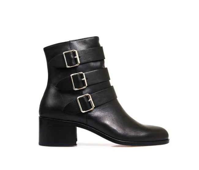 Black ankle boot with block heel and three silver buckled straps on the side.