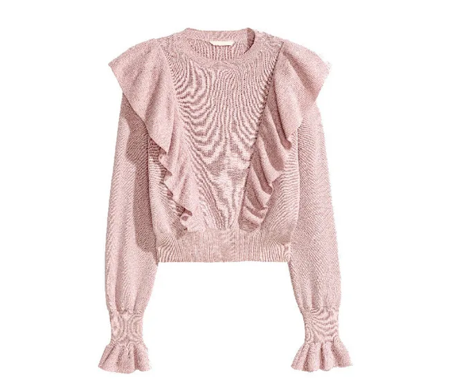 Pink knitted sweater with ruffled details on the front and sleeves, featuring a round neckline.