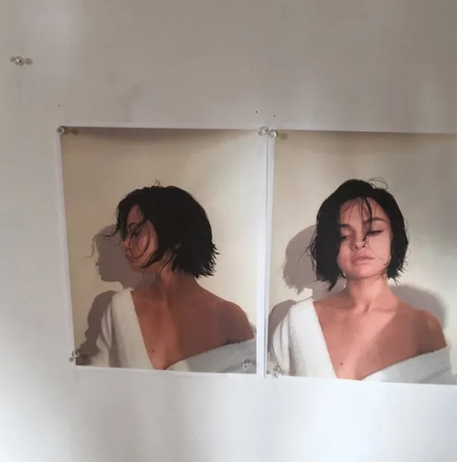 Two identical posters of a person with short hair in a white robe, pinned to a wall.