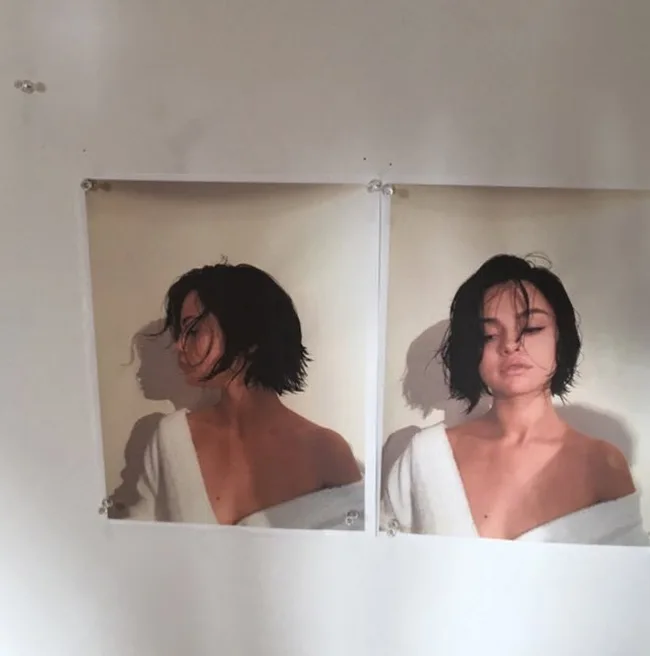 Two identical posters of a person with short hair in a white robe, pinned to a wall.